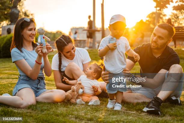 junge familie, die ein spieldate im park hat - play date stock-fotos und bilder