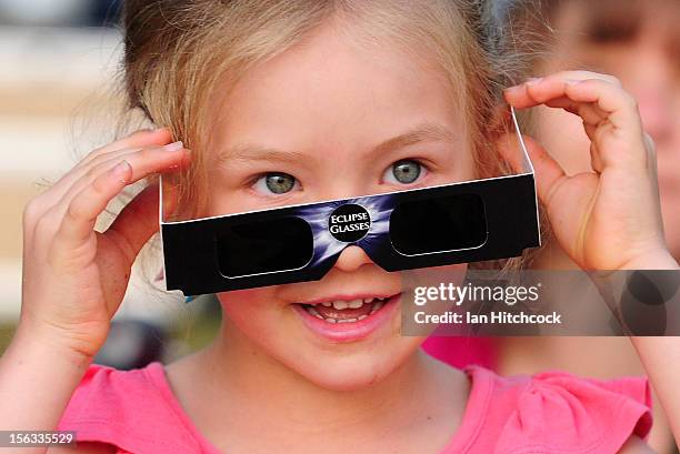 Young girl attempts to view the solar eclipse through special eclipse viewing glasses on November 14, 2012 in Palm Cove, Australia. Thousands of...