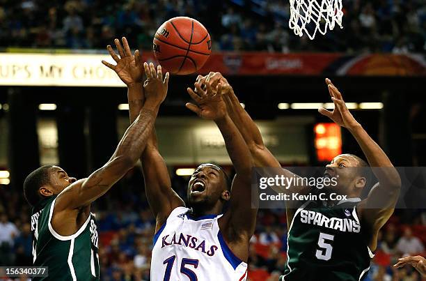 Elijah Johnson of the Kansas Jayhawks has the ball stripped by Keith Appling and Adreian Payne of the Michigan State Spartans during the 2012 State...