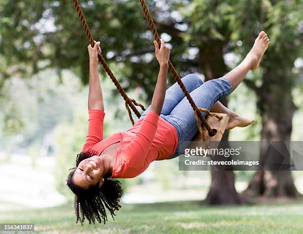 young woman swinging in park - jeans barefoot stock pictures, royalty-free photos & images