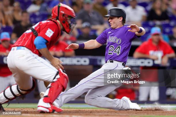 Ryan McMahon of the Colorado Rockies slides home to score a run against the Miami Marlins during the ninth inning at loanDepot park on July 22, 2023...