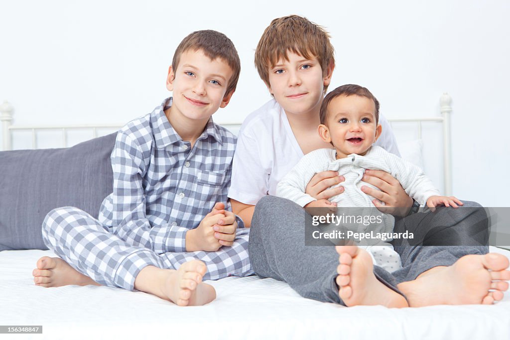 Three brothers sitting on bed