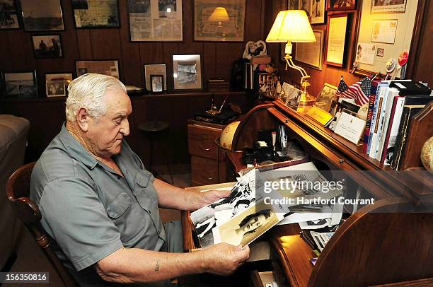 George Mendonsa compares a photograph of his wife to the famous Times Square photograph by Alfred Eisenstaedt, at his Middletown, Rhode Island home,...