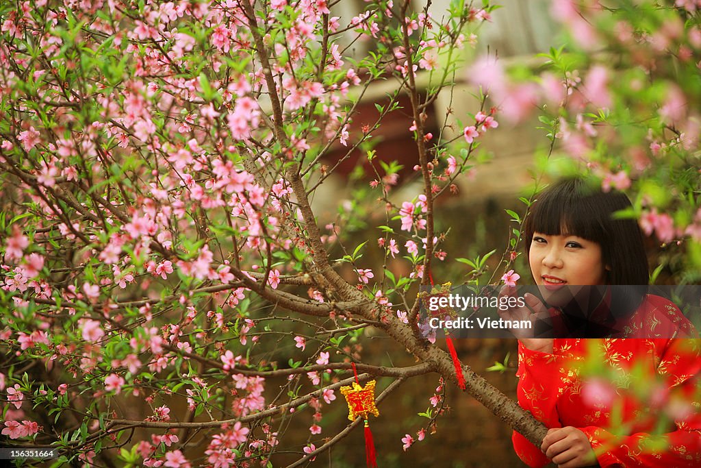 Girl in red beside peach blossom