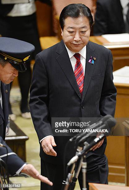 Japanese Prime Minister Yoshihiko Noda is led to his seat by a guard for a one-on-one debate with president of the main opposition Liberal Democratic...
