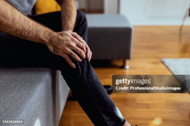an unrecognizable man holding his injured knee - injured knee stock pictures, royalty-free photos & images
