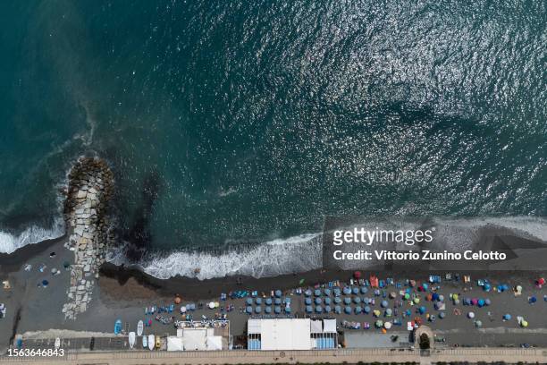 In an aerial view, people lay on the beach and swim in the sea on July 22, 2023 in Genoa, Italy. The government has issued red alerts for 16 cities...