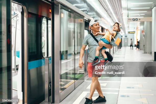 father and son standing together at subway station - jakarta stock pictures, royalty-free photos & images