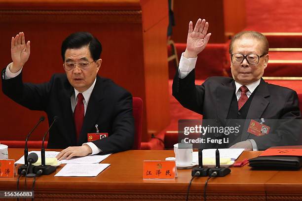 China's President Hu Jintao and former President Jiang Zemin raise their hands as they take a vote during the closing session of the 18th National...