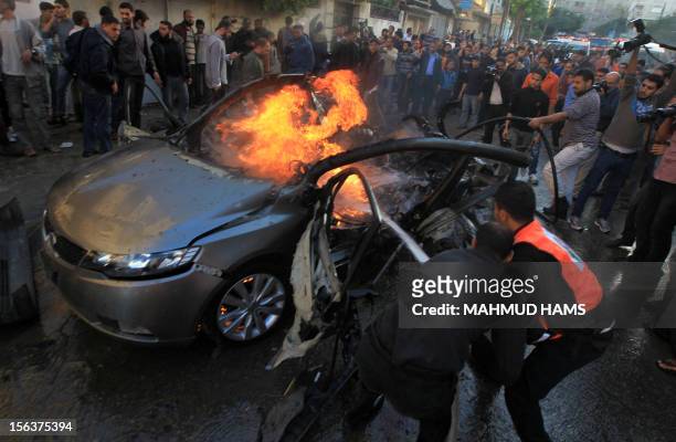Palestinians extinguish fire from the car of Ahmed Jaabari, head of the military wing of the Hamas movement, the Ezzedin Qassam Brigades, after it...