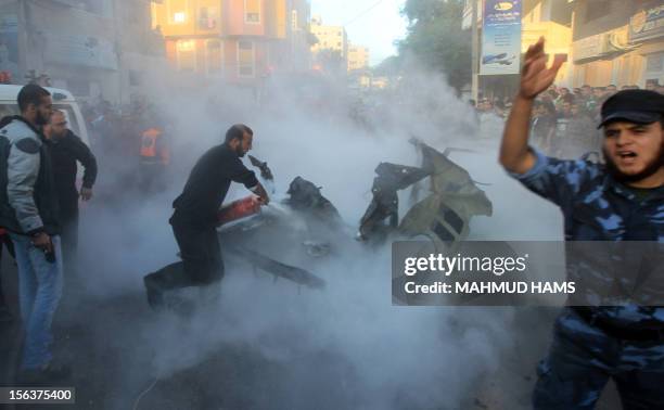 Palestinians extinguish fire from the car of Ahmed Jaabari, head of the military wing of the Hamas movement, the Ezzedin Qassam Brigades, after it...