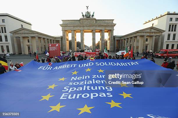 Protesters demonstrating in solidarity with the economically-stricken nations of southern Europe hold taut a giant flag of the Euroepan Union with...