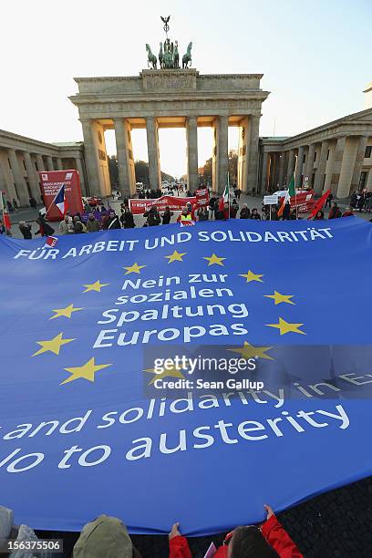 Protesters demonstrating in solidarity with the economically-stricken nations of southern Europe hold taut a giant flag of the Euroepan Union with...