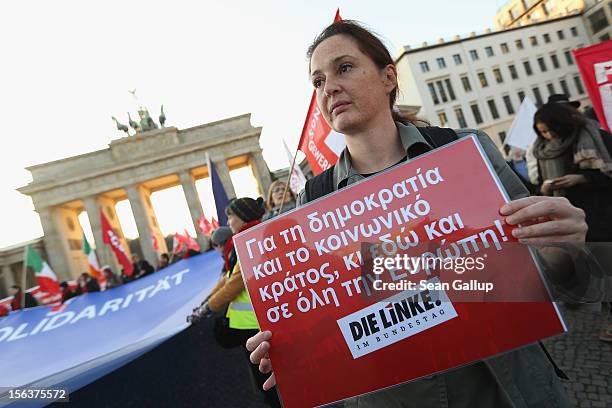 Protesters, including one that holds a sign in Greek that reads: "Defend democracy and a socially-oriented state here and in Europe!," demonstrate in...