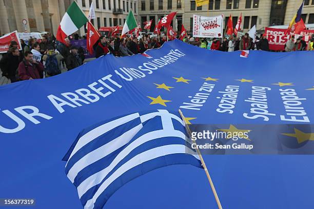 Greek flag waves over a giant flag of the European Union with slogans that read: "For Work And Solidairty, No To The Division Of Europe" during a...