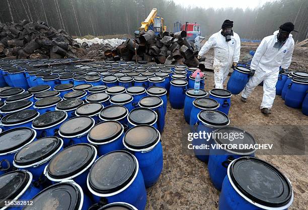 Belarus Emergencies Ministry employees carry new plastic barrels containing pesticides in a forest near the village of Novaya Strazha, some 200 km...