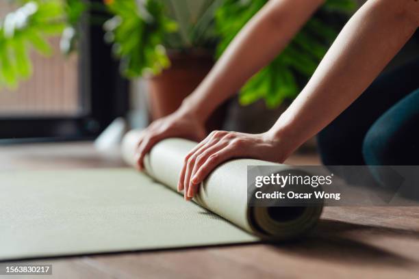 close-up of female hand folding yoga mat after workout - tapis de sol photos et images de collection