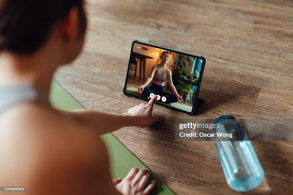 Young Asian woman taking online yoga class at home