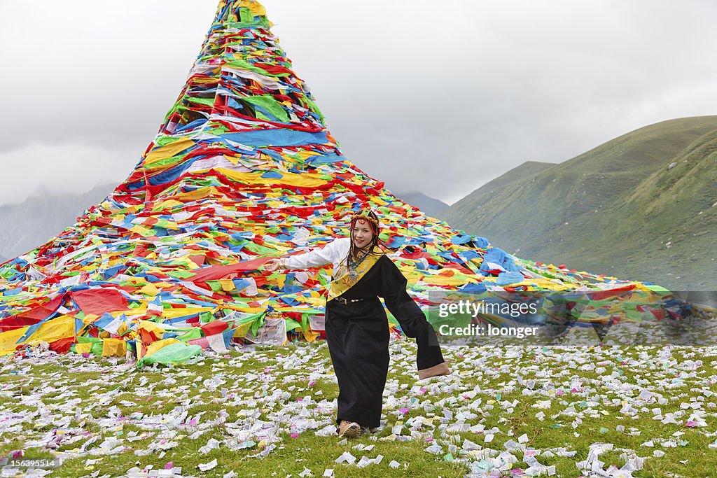 Tibetan girl praying before the prayer flags