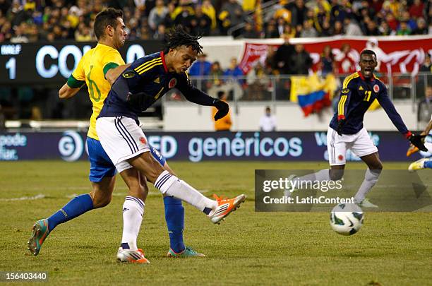 Juan Guillermo Cuadrado of Colombia kicks a goal in front of Leandro Castan of Brazil during a FIFA Friendly match between Colombia and Brazil at...