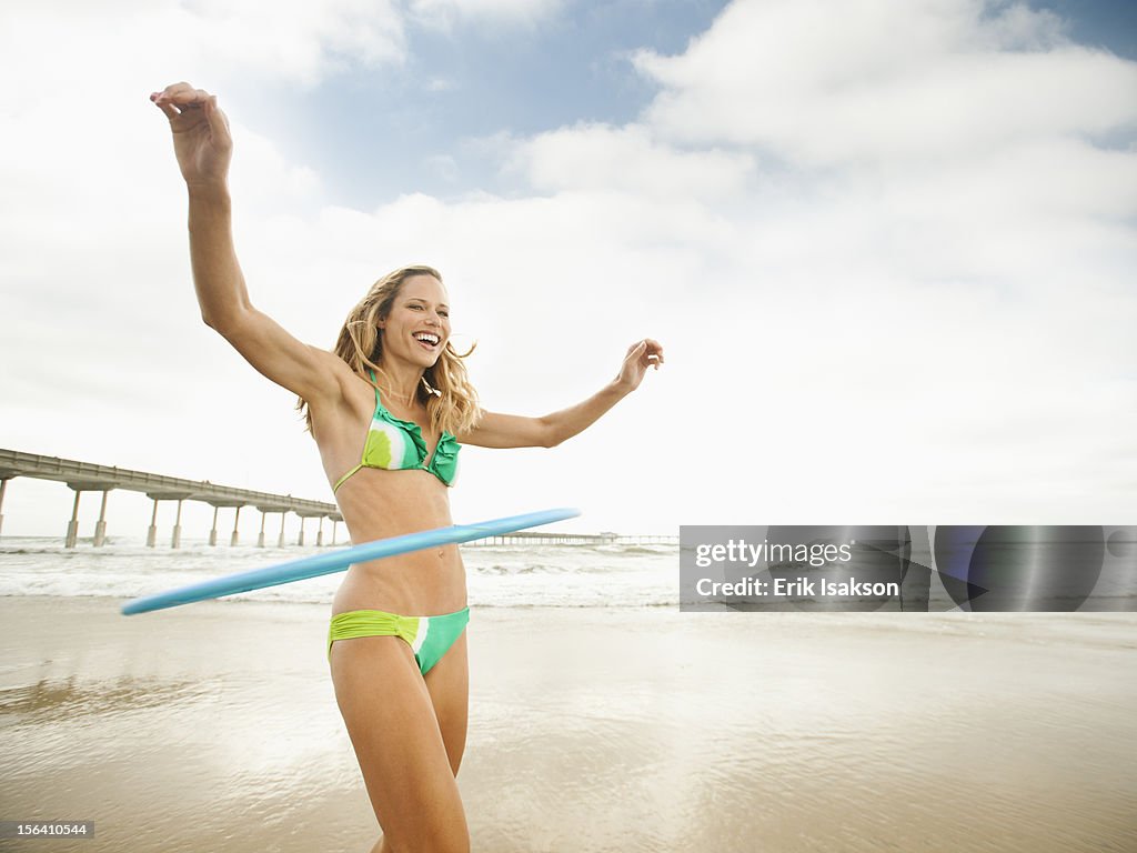 Caucasian woman using plastic hoop on beach