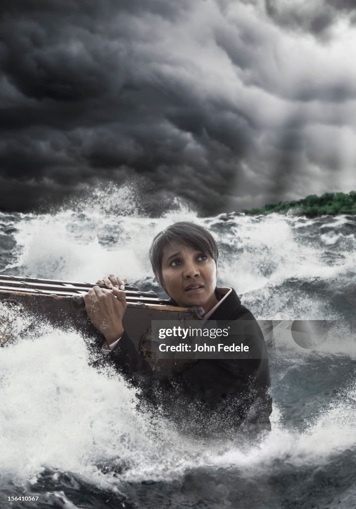 Mixed race woman clinging to trunk in stormy sea