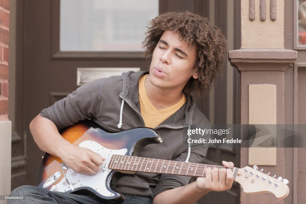 Mixed race teenager playing electric guitar and whistling