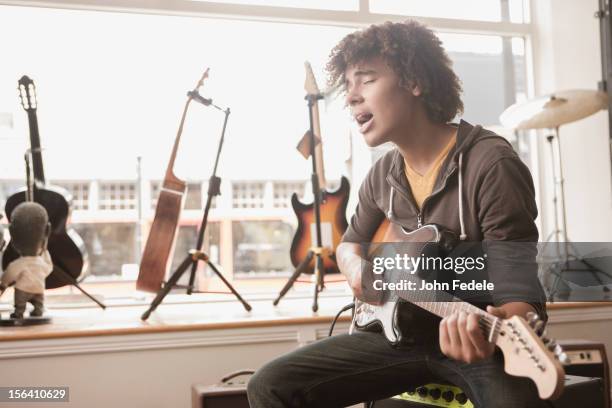 mixed race teenager playing electric guitar and singing - guitar shop stock pictures, royalty-free photos & images