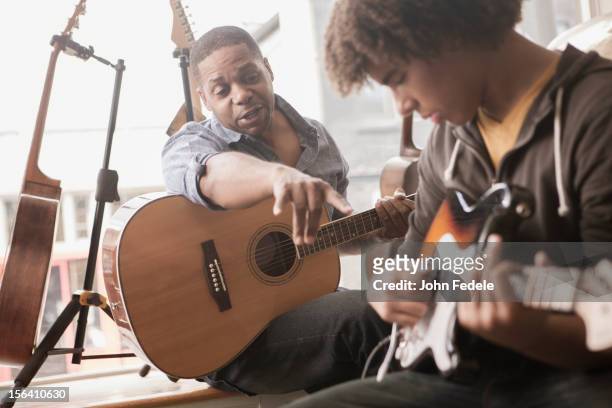 father explaining electric guitar to teenager - learn guitar stockfoto's en -beelden