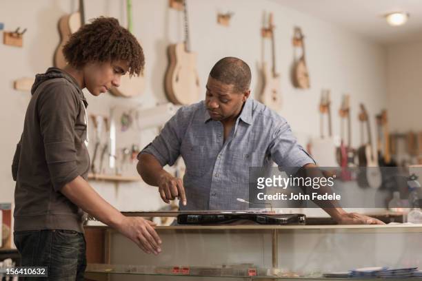 father and son in music workshop - music shop stock pictures, royalty-free photos & images