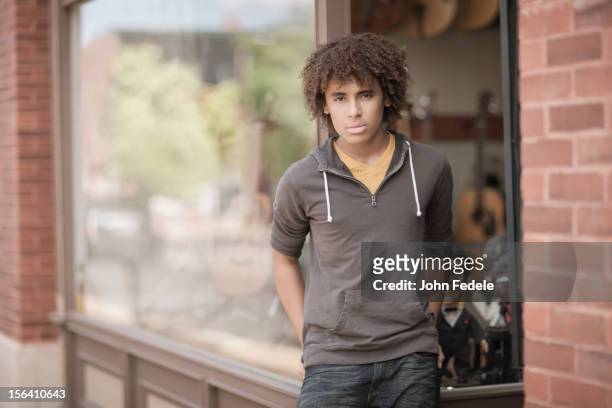 mixed race teenager standing outside music store - teenager boy shopping stock-fotos und bilder