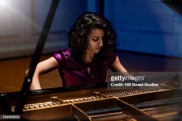 middle eastern woman playing piano - student on stage stock-fotos und bilder