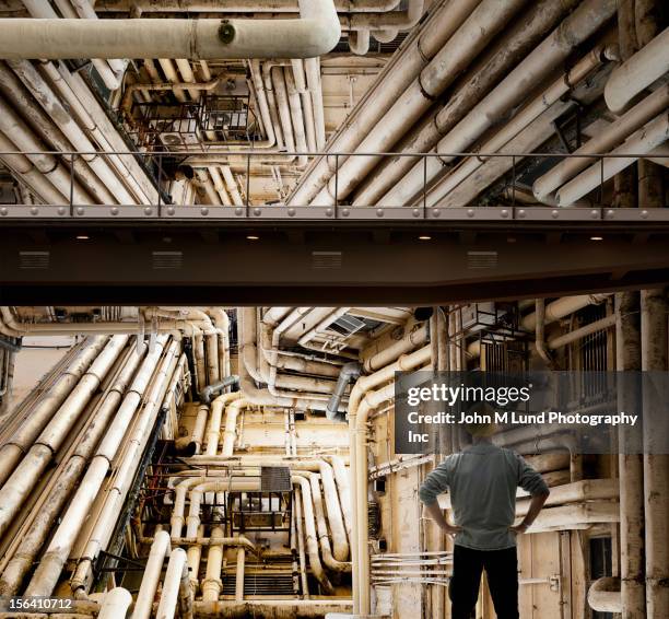 caucasian worker looking at piping in factory - complex fotografías e imágenes de stock