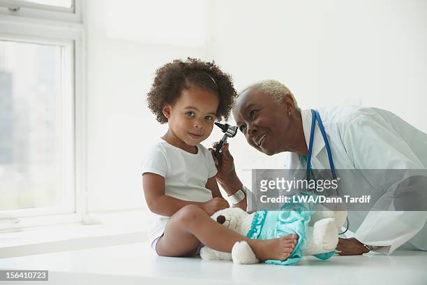 black doctor examining girl - doctor african child stock-fotos und bilder