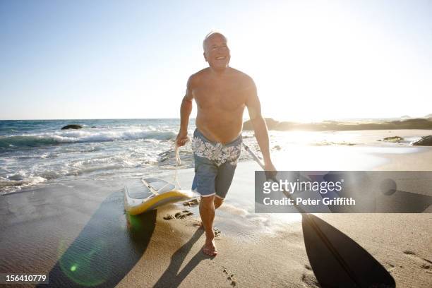 caucasian man pulling paddleboard - paddle surf stock pictures, royalty-free photos & images