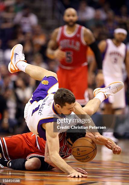 Goran Dragic of the Phoenix Suns falls over Kirk Hinrich of the Chicago Bulls as the battle for a loose ball during the NBA game at US Airways Center...