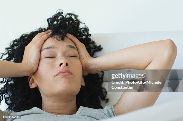 young woman holding her head, eyes closed - hungover stock pictures, royalty-free photos & images