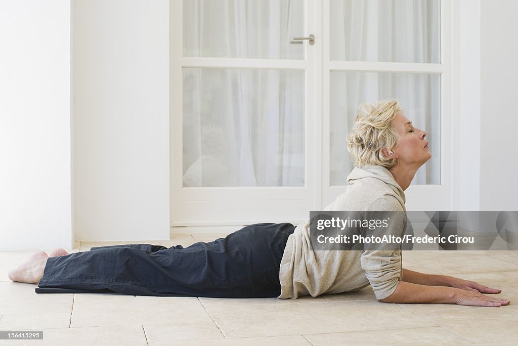 Mature woman doing cobra pose with eyes closed