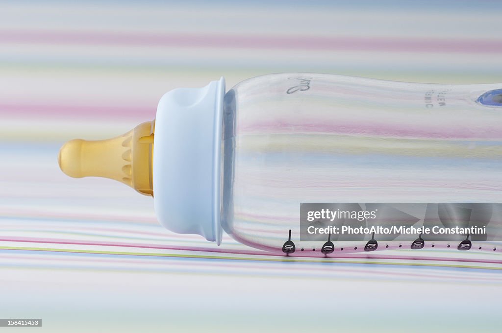 Empty baby bottle on striped background