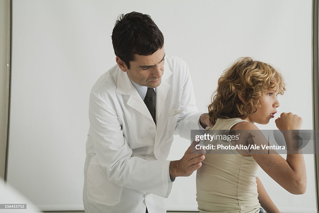 Doctor checking young patient's cough
