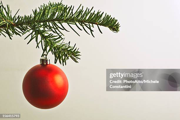 red christmas bauble hanging from christmas tree - weihnachtskugel stock-fotos und bilder