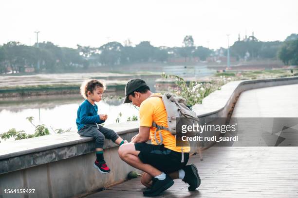 father helping his son put his shoes on when running on the park - lace fastener stock pictures, royalty-free photos & images