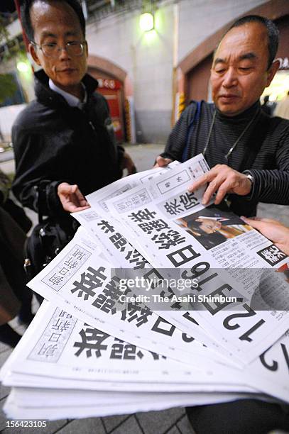 Commutors pick up an extra edition of a newspaper reporting the news about Japanese Prime Minister Noda's remark during one-on-one debate with...