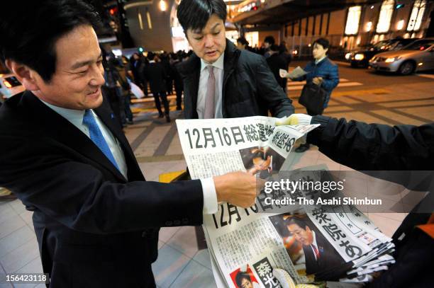 Commutors pick up an extra edition of a newspaper reporting the news about Japanese Prime Minister Noda's remark during one-on-one debate with...