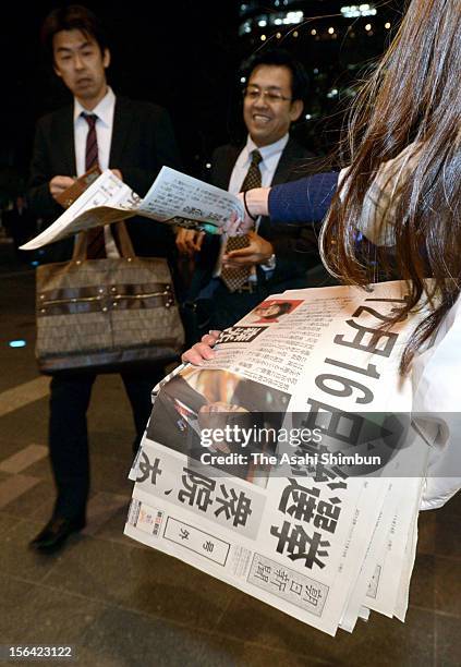 Commutors pick up an extra edition of a newspaper reporting the news about Japanese Prime Minister Noda's remark during one-on-one debate with...