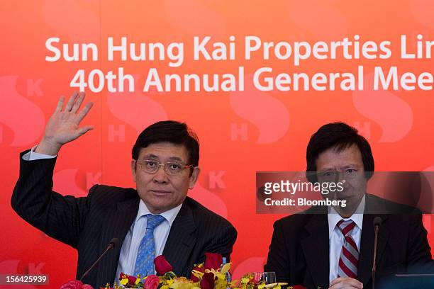 Raymond Kwok, co-chairman of Sun Hung Kai Properties Ltd., left, raises his hand while Thomas Kwok, co-chairman, looks on during a news conference in...