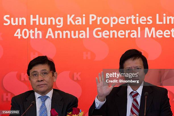 Thomas Kwok, co-chairman of Sun Hung Kai Properties Ltd., right, raises his hand while Raymond Kwok, co-chairman, looks on during a news conference...