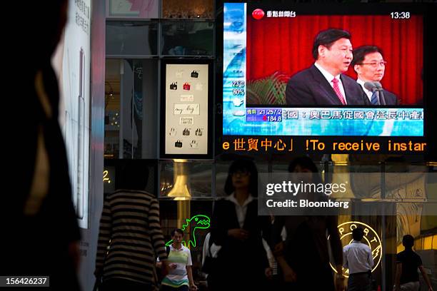 Pedestrians pass by a monitor showing a news broadcast of Xi Jinping, general secretary of the Communist Party of China, outside a mall in the...