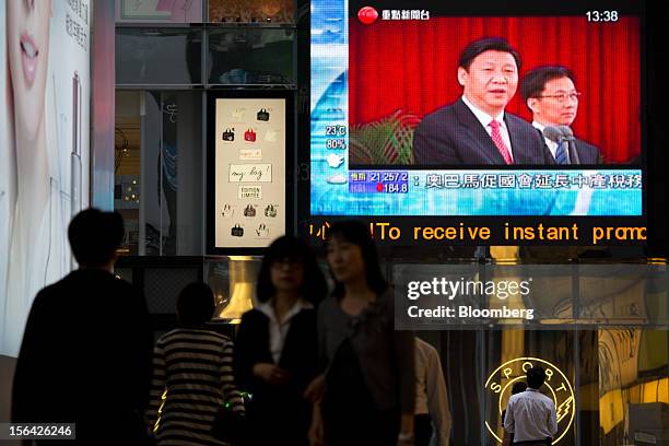 Pedestrians pass by a monitor showing a news broadcast of Xi Jinping, general secretary of the Communist Party of China, outside a mall in the...