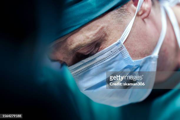 experienced surgeon  operating on patient - successful treatment in hospital operating room - surgical mask man stock pictures, royalty-free photos & images